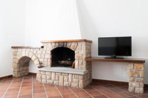 a living room with a stone fireplace with a flat screen tv at Villa Alloro in Massa Lubrense