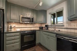 een keuken met groene kasten en een magnetron bij Beaver Village Unit #0514 in Winter Park