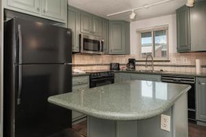 een keuken met groene kasten en een zwarte koelkast bij Beaver Village Unit #0514 in Winter Park
