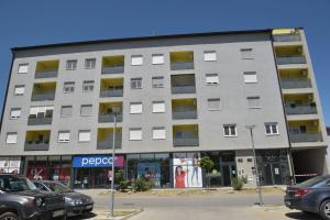 a large building with cars parked in front of it at Kutak M in Bečej