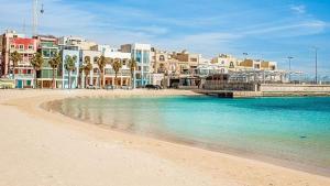 a beach with buildings and palm trees and the water at Family Apartment 2 in Bubaqra