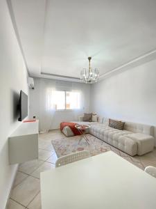 a white living room with a couch and a tv at Shams luxury home in Martil