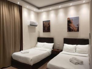 two beds in a hotel room with white sheets at Talaat Harb Hotel in Cairo