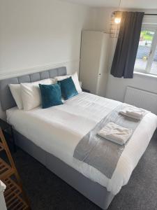 a bedroom with a large white bed with blue pillows at NEW - 3 Bedroom House in East Kilbride in East Kilbride