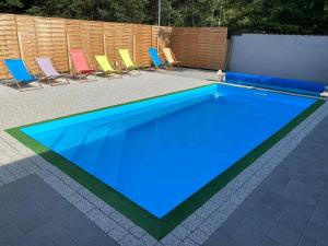a blue swimming pool with chairs and a fence at Pastelowe Borne SRC in Borne Sulinowo