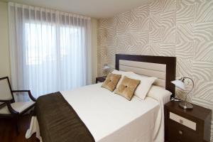 sypialnia z dużym białym łóżkiem i oknem w obiekcie APARTAMENTOS DE CANELAS SUITES con AMPLIAS TERRAZAS w mieście Portonovo