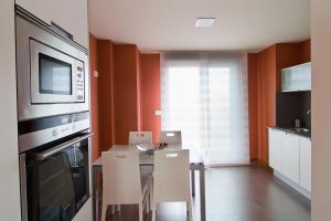 kuchnia ze stołem, krzesłami i kuchenką mikrofalową w obiekcie APARTAMENTOS DE CANELAS SUITES con AMPLIAS TERRAZAS w mieście Portonovo