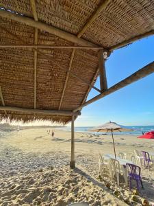 a group of chairs and an umbrella on a beach at Casa Naurú in Fortim