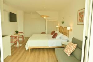 a bedroom with a bed and a table and a couch at Arco da Vella apartamentos in Villanueva de Arosa