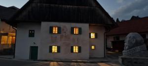 a white house with lights in the windows at night at Apartma Pri Lukšu in Tolmin