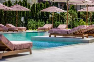 a pool with lounge chairs and umbrellas at J'ADORE Secret Garden A&K Deluxe Studio in Sunny Beach +18 photos