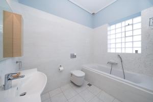 a white bathroom with a tub and a toilet and a sink at Casa Tierra Near ATH Airport in Markopoulo +9 photos