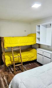 a bedroom with two bunk beds with yellow sheets at Caleta Olivia Ancla alojamiento departamento in Caleta Olivia