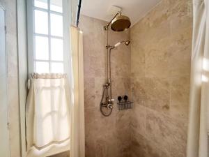 a shower with a shower head in a bathroom at Charme, lumiere, jardin et sauna! in Étretat