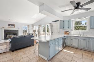 a kitchen with blue cabinets and a ceiling fan at Wishing Whale in Corolla +38 photos