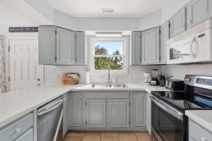 a white kitchen with a sink and a window at Wishing Whale in Corolla
