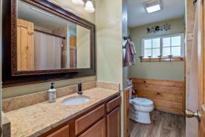 a bathroom with a sink and a toilet and a mirror at Large Yard with Fire Pit Show Low Cabin in Show Low +22 photos
