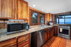 Una cocina con gabinetes de madera y electrodomésticos de acero inoxidable. en Ailina House, en Kailua-Kona