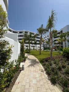 a walkway in front of a building with palm trees at Playa Granada Mar de Fabiola in Motril