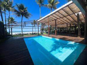 a swimming pool with a pergola and palm trees at 120 Hotel & Beach Club in Guarujá
