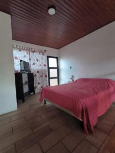 a bedroom with a large bed with a red bedspread at Casa Abierta Playa Juquillal 1 habitacion in Santa Cruz