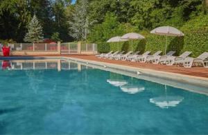 una piscina con sedie e ombrelloni di Bungalow confortable à Saint-Chéron avec piscine a Saint-Chéron