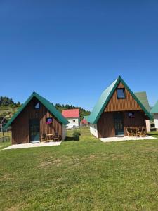 two large wooden buildings with green roofs on a field at Green Valley in Žabljak