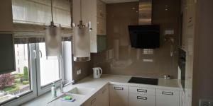 a kitchen with white cabinets and a sink and a window at Apartament Leśna nad jeziorem Długim in Olsztyn
