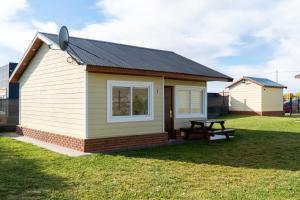 a small house with a picnic table in the grass at Femiba in El Calafate