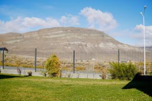 a hill behind a fence with a mountain in the background at Femiba in El Calafate