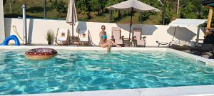 uma mulher está sentada em uma piscina em Panorama Pool Hills em Ledinci