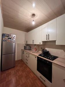 a kitchen with white cabinets and a stainless steel refrigerator at Дом in Bavra