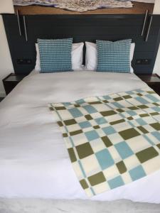 a bed with blue and white sheets and pillows at Posyrooms Apartment in Stalybridge