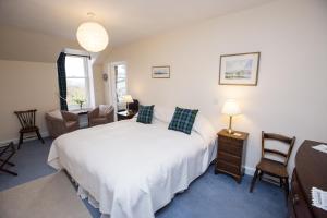 um quarto com uma grande cama branca e cadeiras em Holly Lodge em Strathpeffer