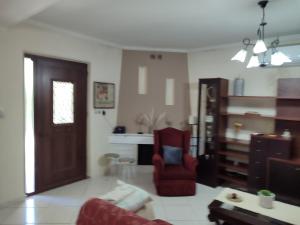 a living room with a red chair and a door at The Green Garden in AGIA VASSA in Chios