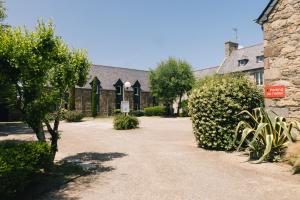 圣马洛Logis Hôtel la Grassinais Saint-Malo的一座种有树木和灌木的房子的庭院