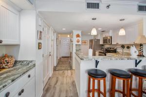 Una cocina con gabinetes blancos y taburetes de bar. en North Breakers #505, en Saint Simons Island