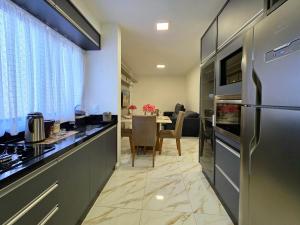 Il comprend une cuisine équipée d'un réfrigérateur et une salle à manger. dans l'établissement Apt Novo 2 Quartos 5 min do Centro e Av Cataratas, à Foz do Iguaçu