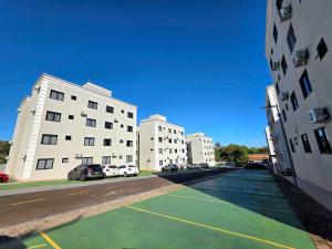 deux bâtiments blancs avec des voitures garées sur un parking dans l'établissement Apt Novo 2 Quartos 5 min do Centro e Av Cataratas, à Foz do Iguaçu