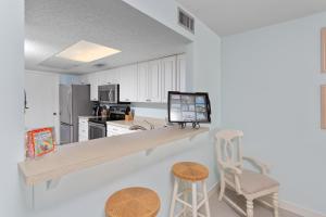 a kitchen with white cabinets and a counter with two stools at North Breakers #407 in Saint Simons Island