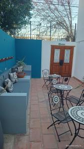 a patio with tables and chairs and a blue wall at La Via Hostel in Neuquén