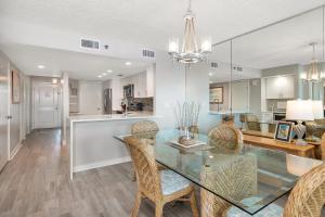 Un comedor y una cocina con una mesa de cristal y sillas. en North Breakers #403, en Saint Simons Island