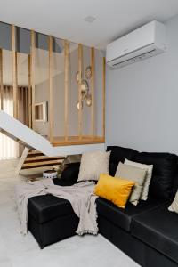 a black couch in a living room with yellow pillows at Casa das Nogueiras in Armamar