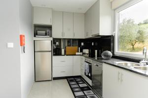 a kitchen with white cabinets and a window at Casa das Nogueiras in Armamar