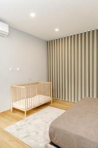 a bedroom with a crib and a window with curtains at Casa das Nogueiras in Armamar