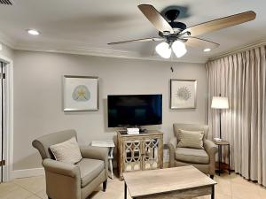 a living room with a ceiling fan and a tv at Inlet Dunes #102 in Inlet Beach