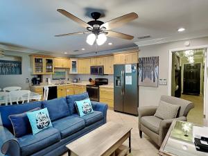 a living room with a blue couch and a kitchen at Inlet Dunes #102 in Inlet Beach