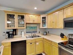 a kitchen with wooden cabinets and a sink at Inlet Dunes #102 in Inlet Beach +19 photos