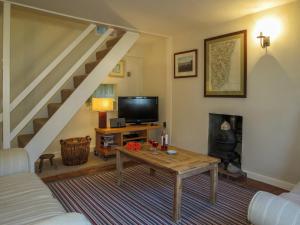 a living room with a table and a staircase at Ivy Cottage in Aldeburgh