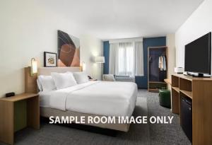 a bedroom with a large white bed and a tv at Spark by Hilton Essex Junction in Essex Junction